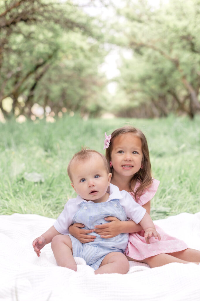 Siblings posing together among orchard trees during a spring photo session in Utah County