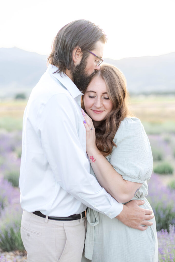 Couple standing together in a blooming lavender field during a romantic summer engagement session in Utah