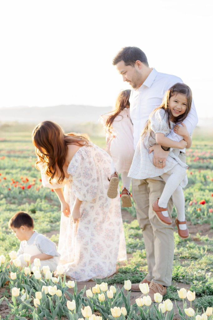 A young family plays together in a field of tulips in Utah