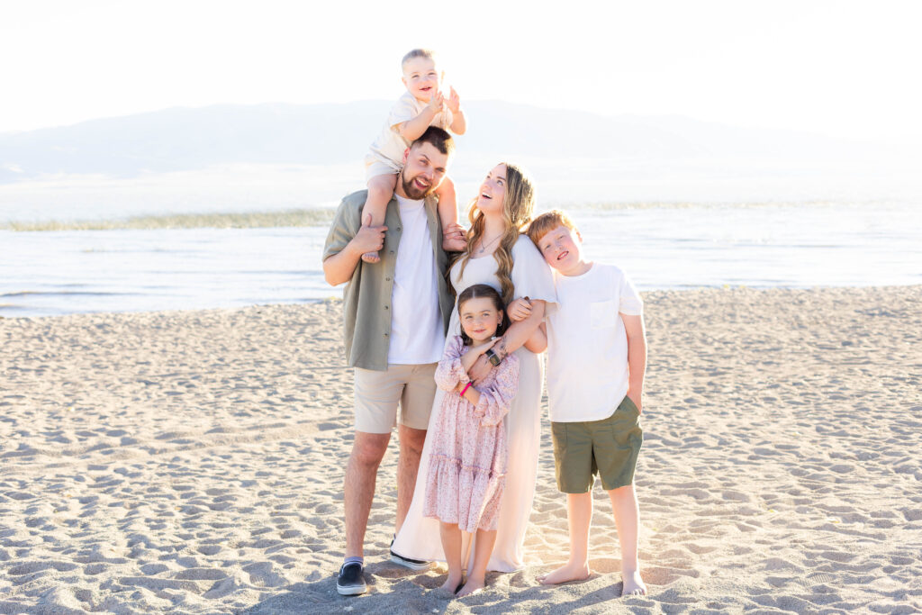 A glowing summer family photo session on the beach in Utah featuring a family enjoying a candid moment of laughter and joy.