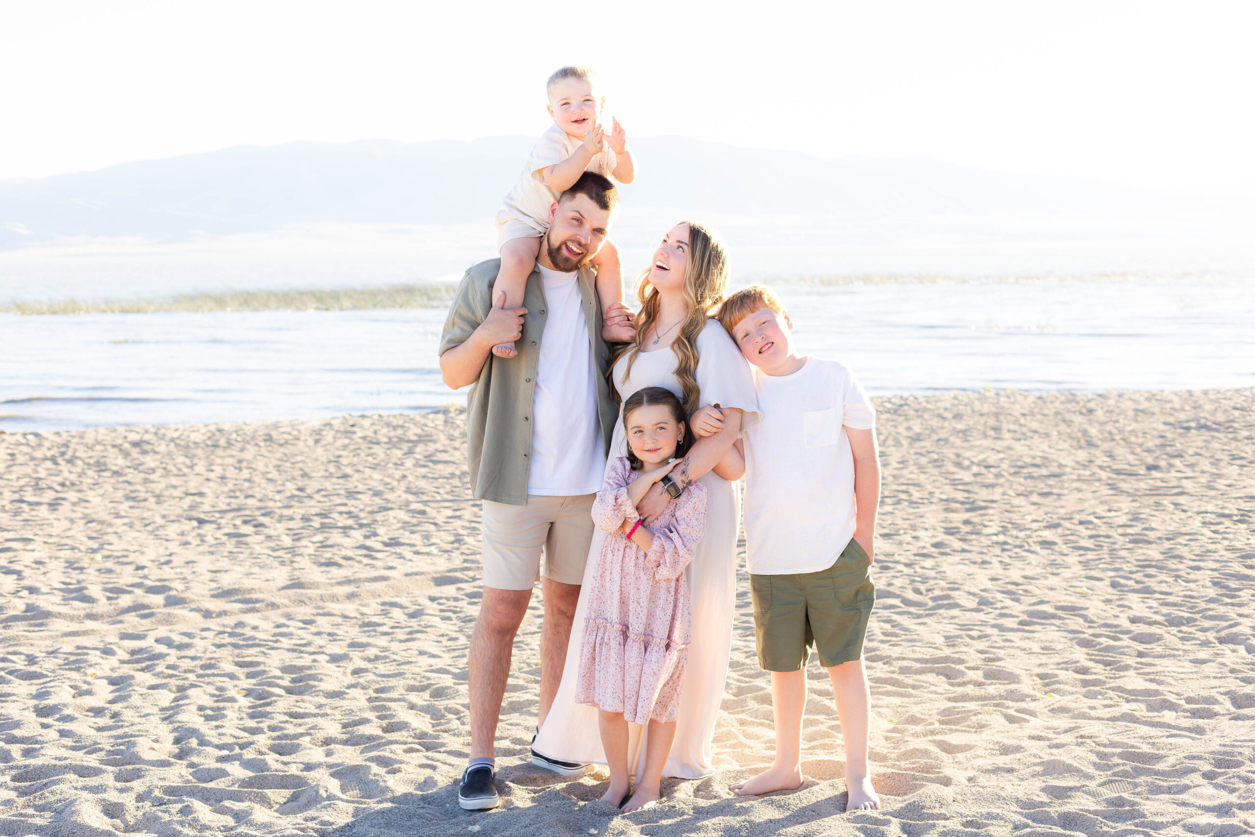 A glowing summer family photo session on the beach in Utah featuring a family enjoying a candid moment of laughter and joy.