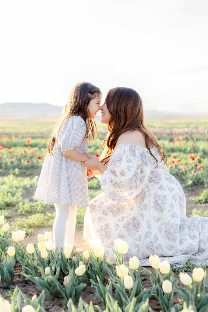 A mom and daughter laughingly touch noses in a beautiful field of tulips in Utah