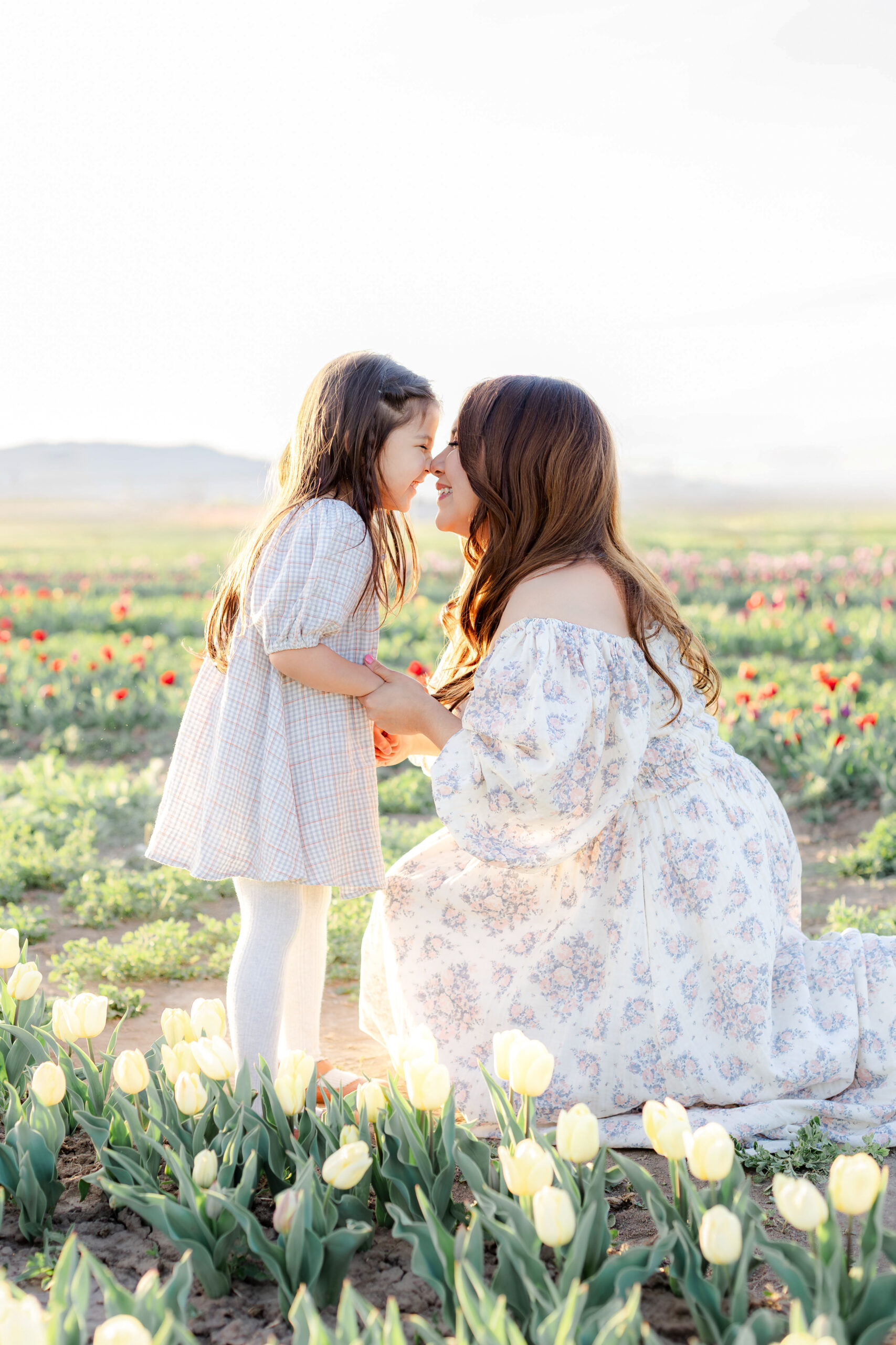 A mom and daughter laughingly touch noses in a beautiful field of tulips in Utah