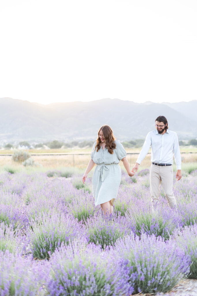 Couple walking together through a blooming lavender field in Utah during a relaxed summer photo session