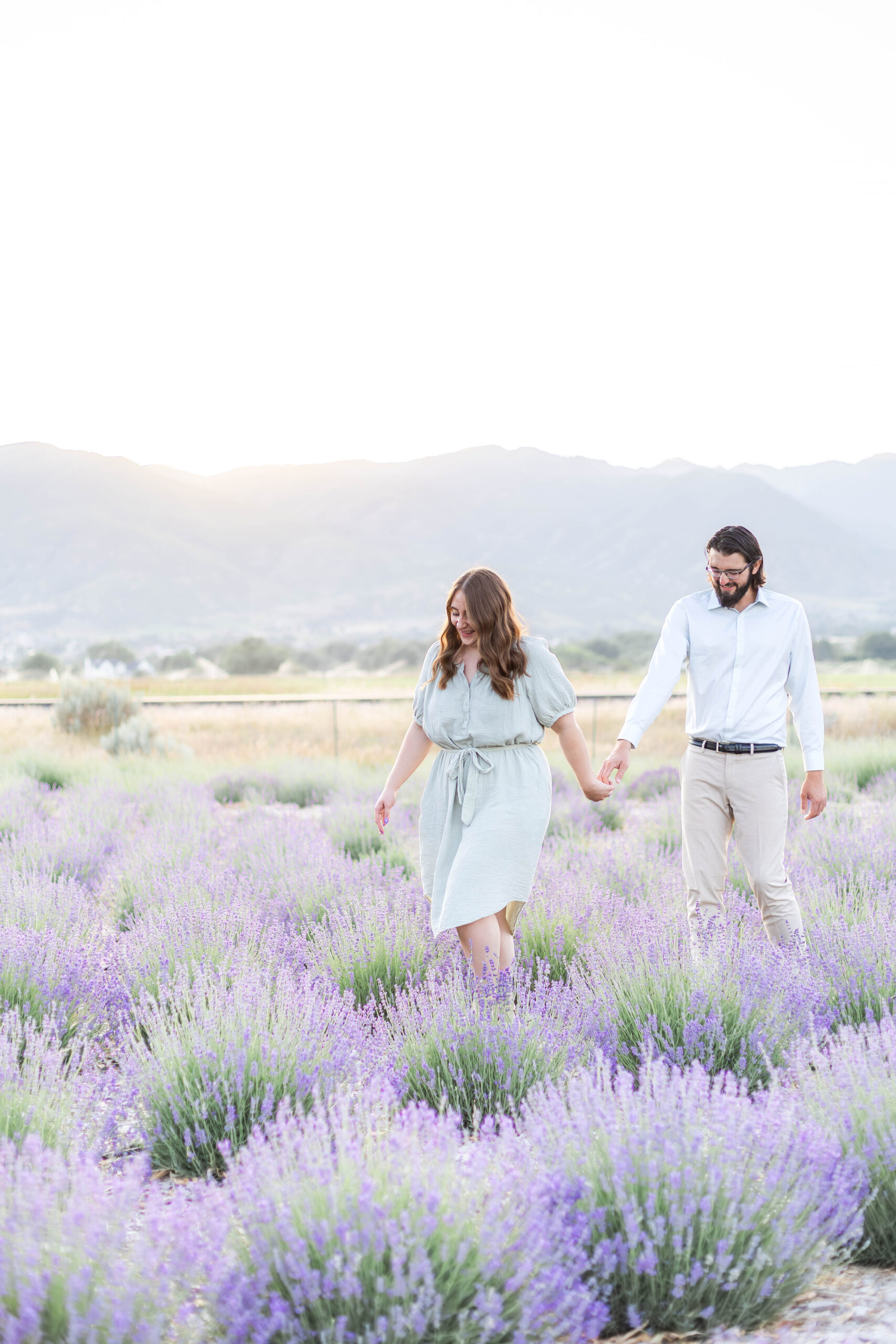 Couple walking together through a blooming lavender field in Utah during a relaxed summer photo session