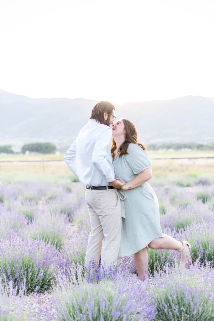 Engaged couple standing close in a Utah lavender field surrounded by soft purple blooms at sunset