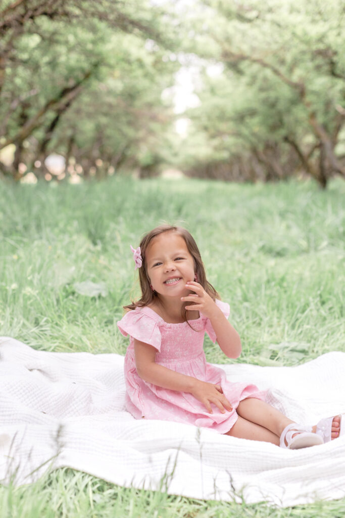A child laughing with joy during a spring orchard family photography session in Utah.